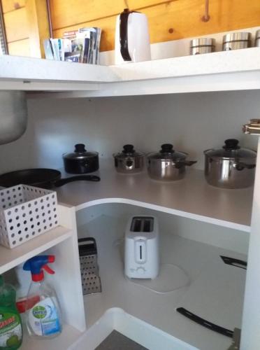 a kitchen shelf with pots and pans on it at Cosy n Central Rotorua 2BR Entire House & Studio -summer only in Rotorua