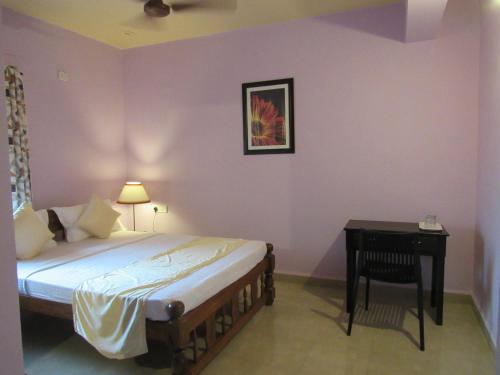 a bedroom with a bed and a table with a lamp at TGF Dream Guest House in Majorda