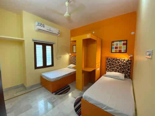 a small bedroom with two beds and a window at Backpackers Den in Lucknow