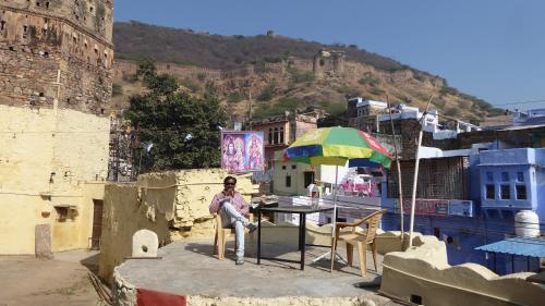 a woman sitting at a table with an umbrella at Haveli Elephant Stable in Būndi