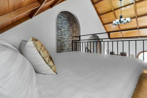 a bedroom with a large white bed with a wooden ceiling at Little Colmar - Homestay & Pottery Studio in Ha Long