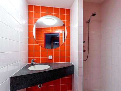 an orange tiled bathroom with a sink and a mirror at Hotel Rhynern Nord in Rhynern