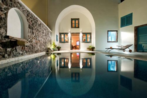 a swimming pool in a home with a stone wall at Vallas Apartments & Villas in Firostefani