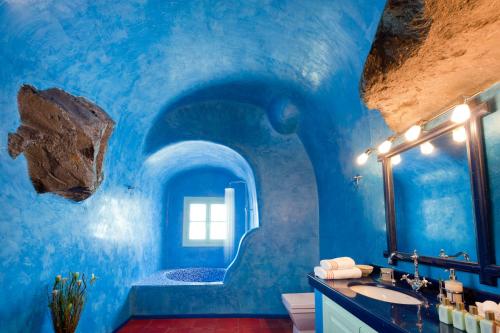 a blue bathroom with a sink and a mirror at Vallas Apartments & Villas in Firostefani