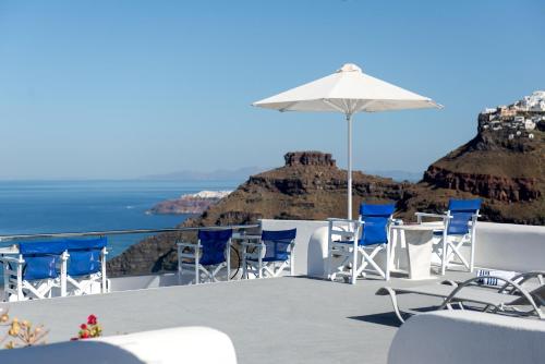 a patio with chairs and an umbrella and the ocean at Vallas Apartments & Villas in Firostefani