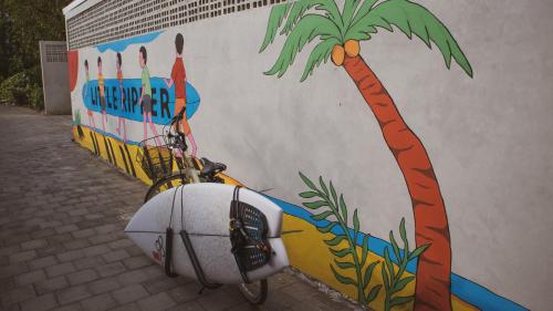 a bike parked in front of a wall with a palm tree at Little Ripper Boutique Lofts in Tanah Lot