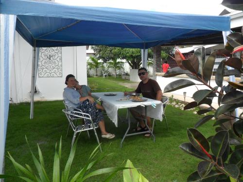 two people sitting at a table under a blue canopy at Jasmin's Room Rental in Moalboal
