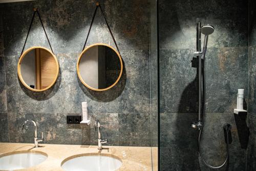 two sinks in a bathroom with two mirrors at Safestay Kitzbühel Centre in Kitzbühel