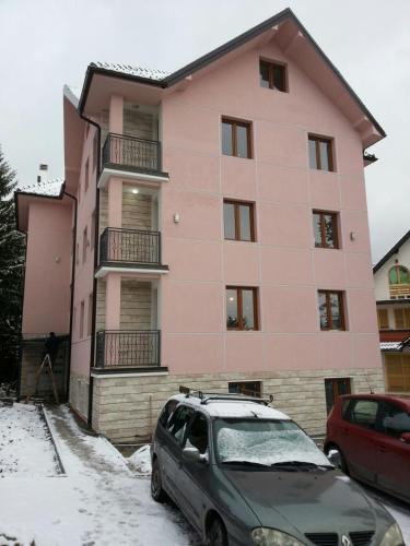 a pink building with a car parked in front of it at Vila Meridijan in Zlatibor