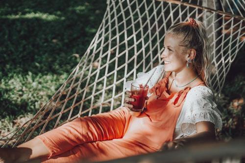 a woman sitting on a hammock holding a drink at Cliff Stories in Varkala