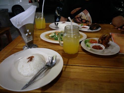 uma mesa de madeira com pratos de comida e bebidas em Pica Sedana Homestay em Ubud