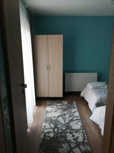 a bedroom with blue walls and a bed and a rug at Къща За Гости Уют Guest House Cozy in Starosel