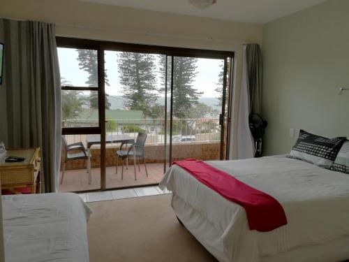 a bedroom with two beds and a balcony with a view at Rockview Guest House in Port Edward