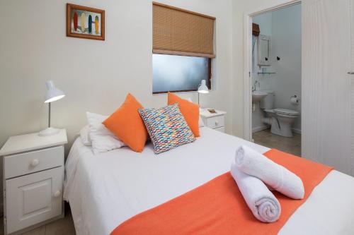 a bedroom with a large white bed with orange pillows at Aloe Again in Jeffreys Bay