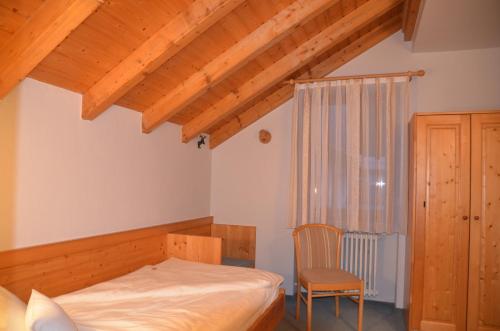 a bedroom with a bed and a chair at Hotel-Pension Breig Garni in Ottenhöfen