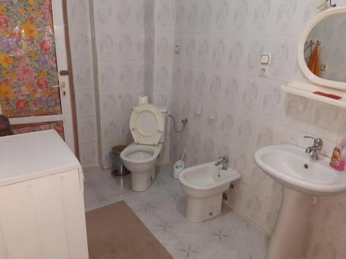 a white bathroom with a toilet and a sink at Armand's home in Korçë