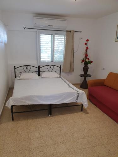 een slaapkamer met een bed en een rode bank bij Adam s apartments entrance to Neve Zohar in Neve Zohar