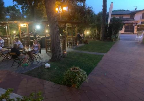 a group of people sitting at tables in a yard at night at Hotel Storyville - svago e convenzioni aziendali in Cinquale