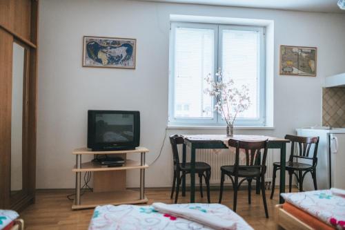 a living room with a table with chairs and a television at Klub U Námořníka in Dvůr Králové nad Labem