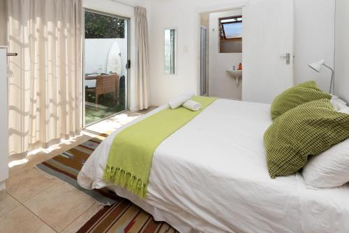 a bedroom with a large white bed with green sheets at Aloe Again in Jeffreys Bay