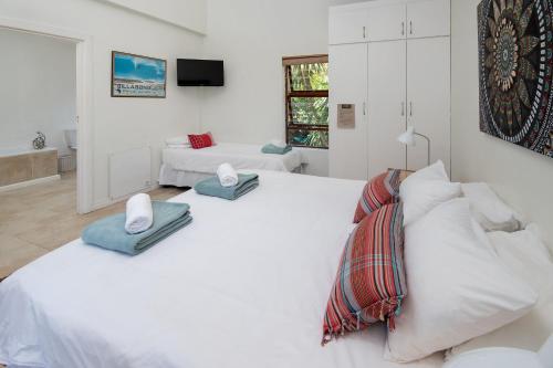 a white bedroom with two beds and a television at Aloe Again in Jeffreys Bay