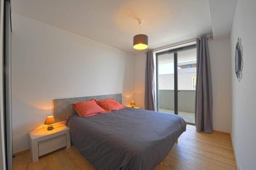 ein Schlafzimmer mit einem Bett mit zwei roten Kissen und einem Fenster in der Unterkunft Bel appartement vue mer Porto Vecchio in Porto-Vecchio