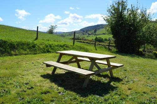a wooden picnic table in a field of grass at Drumahaman Cottage in Ballycastle