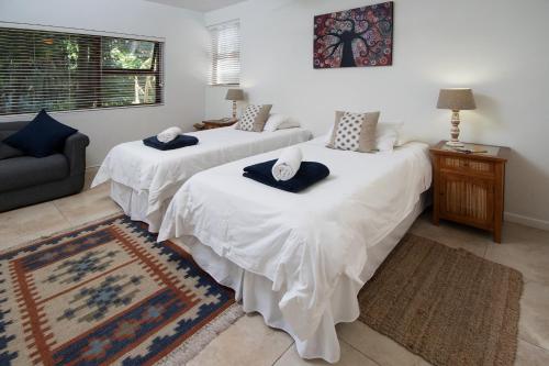 two beds in a room with a couch and a rug at Aloe Again in Jeffreys Bay