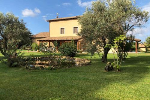 a house with a yard with trees and a pond at Inghirios Wellness Country Resort in Santa Maria la Palma