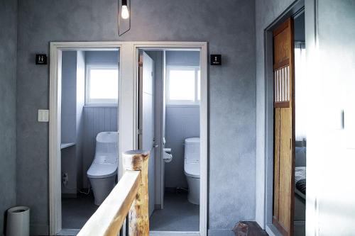 a bathroom with two toilets and a sink and two windows at The Apartment Hotels KOU in Otaru