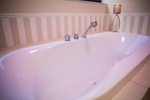 a large white bath tub with a faucet in a bathroom at Hotel Avangarda in Różan