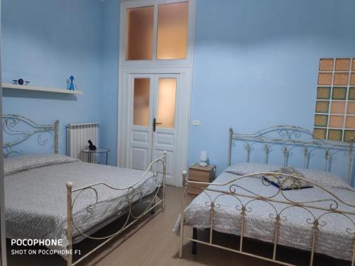 2 camas en una habitación con paredes azules en Napulè 10, en Nápoles