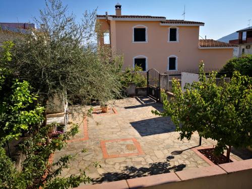 un patio trasero con una casa, árboles y una valla en Casa Il Giardino, en Orosei