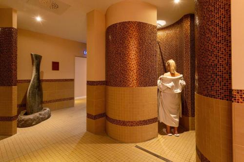 a woman standing next to a tile wall in a bathroom at Seeschloss Schorssow in Schorssow