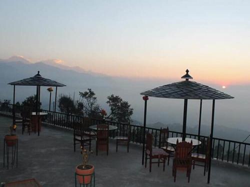 a patio with tables and chairs and umbrellas at Lake View Lodge Sarangkot in Pokhara