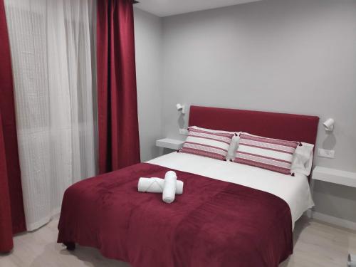 a bed with two white towels on a red blanket at SUITEDREAMS - Boigues 3 in Andorra la Vella