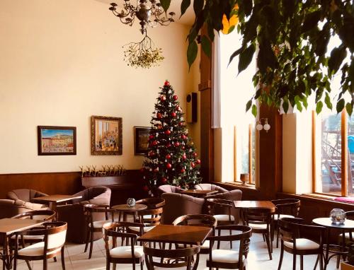 a christmas tree in a restaurant with tables and chairs at Hotel & Penzión Grand Matej in Banská Štiavnica