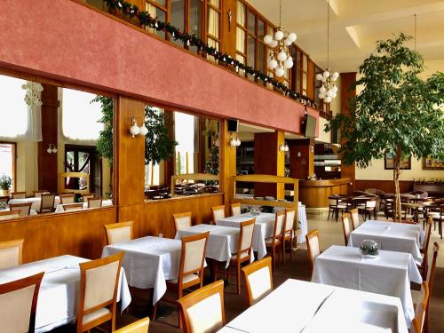 a restaurant with white tables and chairs at Hotel & Penzión Grand Matej in Banská Štiavnica