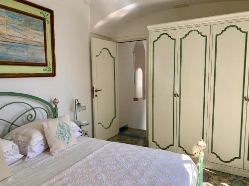 a bedroom with a white bed and a cabinet at Villa Le Baste in Furore