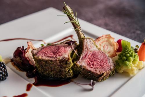 a piece of meat on a white plate with fruit at Hotel Triglav in Bled