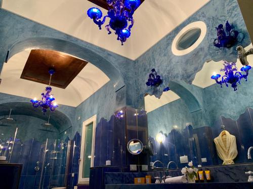 a bathroom with blue walls and blue chandeliers at Villa Le Baste in Furore