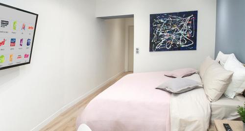 a bedroom with a white bed and a painting on the wall at Apart 1 opera · Modern studio fully furnished in Paris