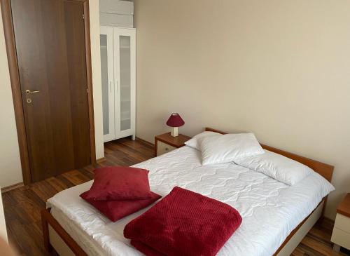 a bedroom with a bed with two red pillows on it at Apartment at White Lavina Hotel in Bansko