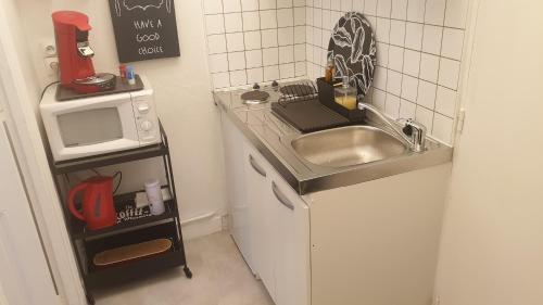 a small kitchen with a sink and a microwave at Le Galope, Appartement centre Compiègne in Compiègne