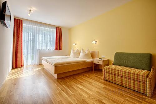 sypialnia z łóżkiem, kanapą i oknem w obiekcie Appartementhaus Berger w mieście Grossarl
