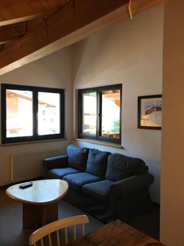 a living room with a blue couch and a table at Apart am Waldnerhof in Ried im Oberinntal
