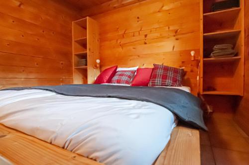 Cama en habitación de madera con almohadas rojas en Ruhige Chalets mit Seeblick in zentraler Lage en Schliersee