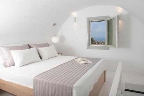 a white bedroom with a bed and a window at White Orchid Suites in Vóthon