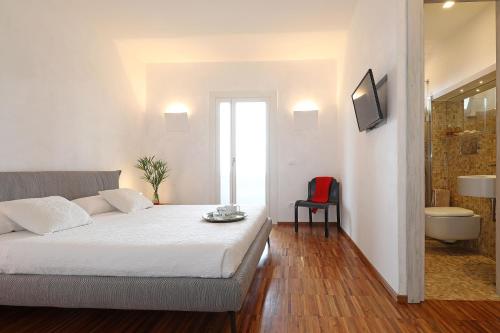 a white bedroom with a bed and a television at Villa Laura Aegilium in Giglio Porto