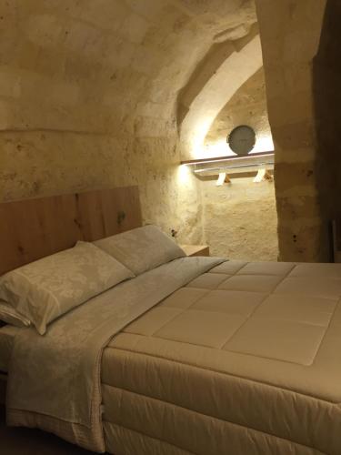 een slaapkamer met een groot bed in een stenen muur bij Porticina Verde Suite in Matera